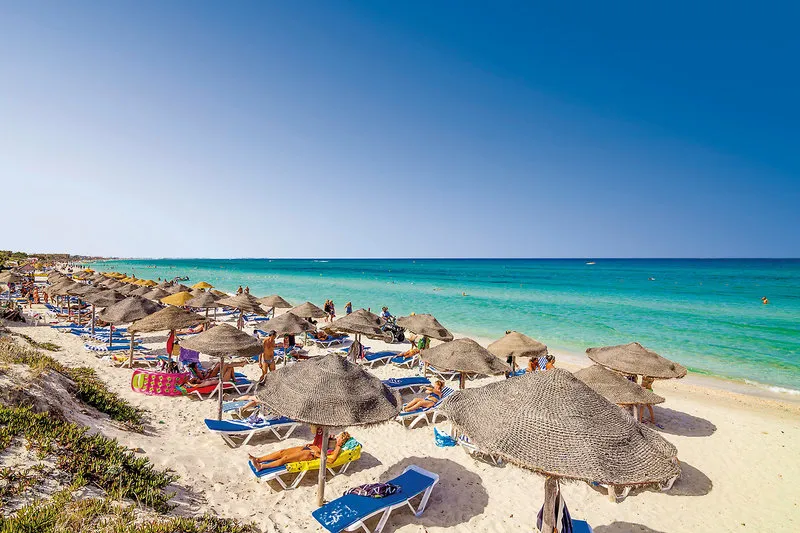 Peščena plaža s slamnatimi senčniki in turkiznim morjem v Mahdii