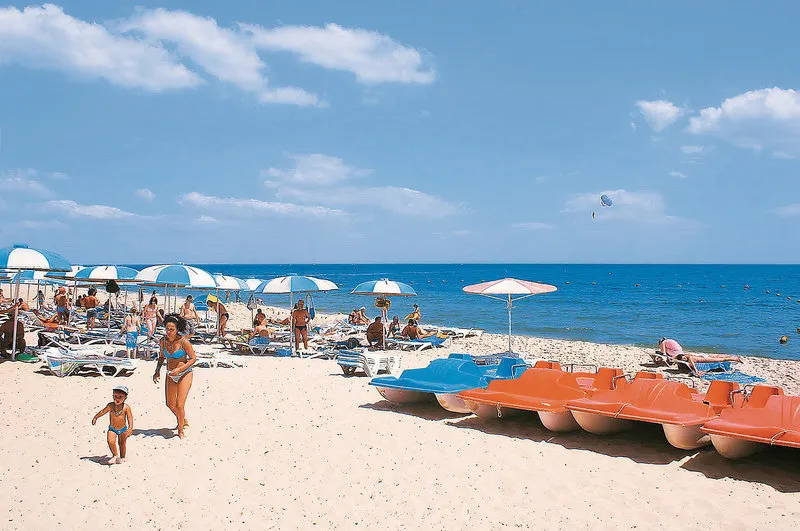 Peščena plaža s pedalini in senčniki
