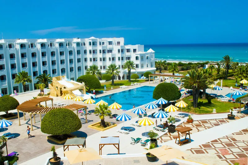 Pogled na bazenski kompleks in turkizno morje v ozadju