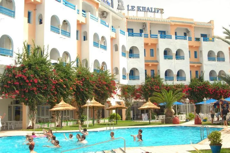 Zunanji bazen hotela Le Khalife z obiskovalci in palmami v Hammametu