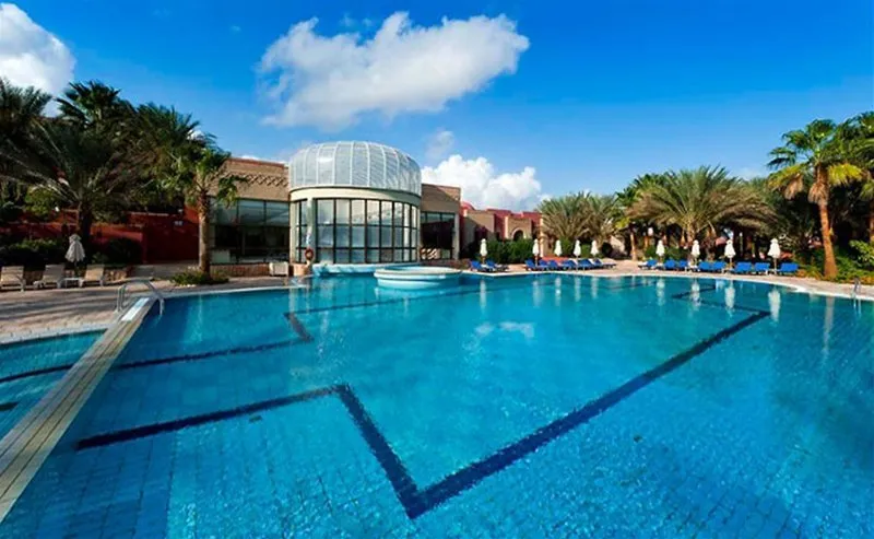 Velik zunanji bazen obdan s palmami pod modrim nebom